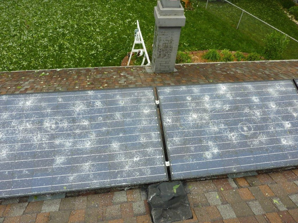 Close-up of hail damage on a Nebraska roof with solar panels nearby